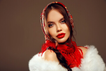 Fashion woman portrait with traditional red headscarf. Russian beauty girl model with red lips makeup isolated on studio background.