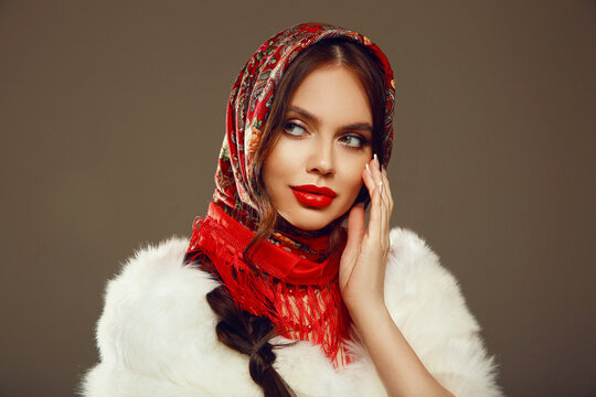 Fashion woman portrait with traditional red headscarf. Russian beauty girl model with red lips makeup and manicured nails isolated on studio background.