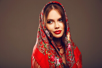 Russian girl style. Fashion woman portrait with traditional red headscarf. Beauty girl model with red lips makeup isolated on studio background.