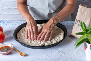 Spreading the pizza dough on the baking dish.