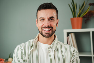 Close up portrait of one handsome guy with perfect white teeth smiling at home. Front view of young confident man with friendly and positive expression. Happy adult male laughing and looking at camera