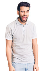 Fototapeta premium Young handsome man with beard wearing casual polo winking looking at the camera with sexy expression, cheerful and happy face.