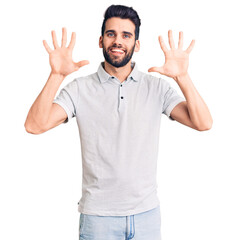 Naklejka premium Young handsome man with beard wearing casual polo showing and pointing up with fingers number ten while smiling confident and happy.