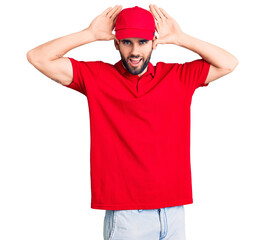 Young handsome man with beard wearing delivery uniform smiling cheerful playing peek a boo with hands showing face. surprised and exited