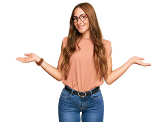 Young hispanic woman wearing casual clothes and glasses smiling showing both hands open palms, presenting and advertising comparison and balance - obrazy, fototapety, plakaty
