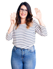Beautiful young brunette woman wearing casual clothes and glasses showing and pointing up with...