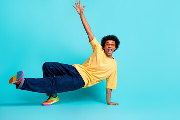 Full size photo of talented cool man wear oversize t-shirt denim pants in glasses dancing hip hop isolated on teal color background