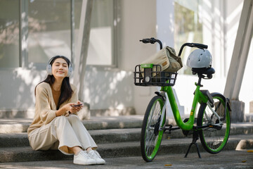 Asian businesswoman go to work at office stand and smiling wear backpack with bicycle. Bike commuting, Commute on bike, Business commuter concept.