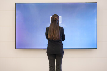 Young businesswoman analyzing data on large screen - 775232288