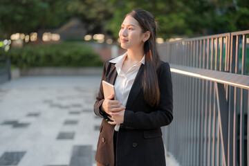 Professional woman works on her tablet while standing outside a modern office building