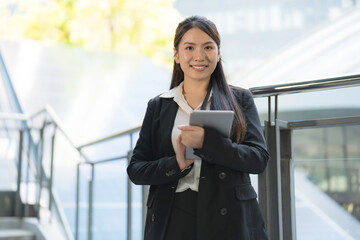 Confident businesswoman holding tablet outdoors - 775232650