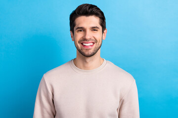 Photo of young nice cheerful man beaming smile wear beige sweatshirt isolated on blue color background