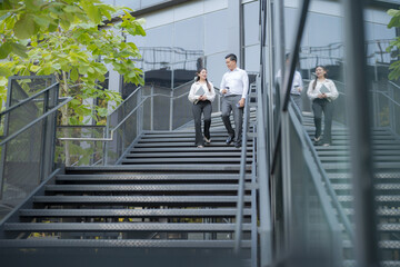 Business colleagues walking downstairs outdoors - 775233241