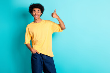 Photo of optimistic guy with afro hairdo dressed yellow t-shirt showing thumb up hand in pocket...