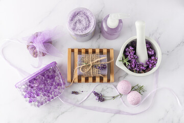 Bathroom products with lavender fragrance. Aroma soap, hydrogel and bath balls, salt in jar, shampoo bottle, sachet and mortar wit dried lavender flowers on marble table background. Top view card.