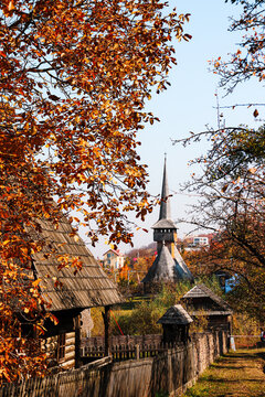 Cluj Napoca, Romania - October 18,2019: Wooden church in distance between autumn colored trees in Ethnographic Park Romulus Vuia