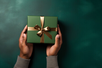  glamorous green background with male hands holding a wrapped gift box seen from above for a birthday 