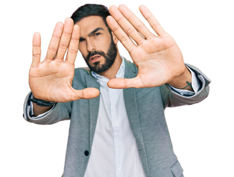 Young hispanic man wearing business clothes doing frame using hands palms and fingers, camera perspective