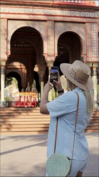 Young female tourist taking photos with her cell phone at the Morisco kiosk in Mexico City
