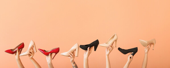 Female hands with different stylish shoes on color background