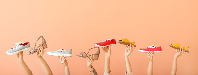 Female hands with different stylish shoes on color background