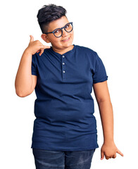 Little boy kid wearing casual clothes and glasses smiling doing phone gesture with hand and fingers like talking on the telephone. communicating concepts.