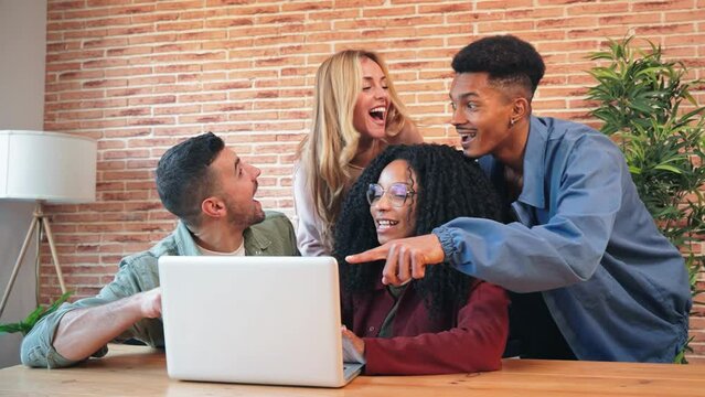 Group of young adult friends having fun using a laptop sharing on the social media. Happy and smling multiracial people browsing online with a computer. Couples watching videos with a notebook at home