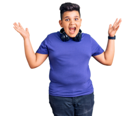 Little boy kid listening to music wearing headphones celebrating crazy and amazed for success with arms raised and open eyes screaming excited. winner concept