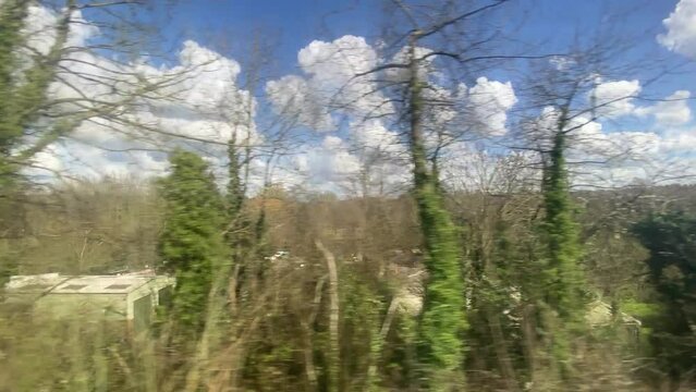 Wide shot countryside & farmland farm clouds and blue sky out of a window of train, tracking along flat british UK southern England  - stock footage video