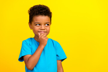 Portrait of cunning tricky schoolboy with afro hair wear blue t-shirt look at offer empty space...