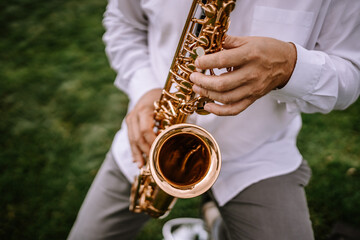 Valmiera, Latvia - Augist 13, 2023 - Close-up of a person playing a golden saxophone, focusing on...