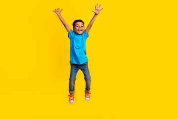 Full size photo of cute little student schoolboy wear blue t-shirt denim pants raising palms fly...