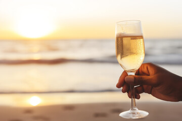 two people African American hands toasting champagne glasses for valentine with a beach background, a celebration or engagement concept 