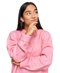 Young asian woman wearing casual winter sweater with hand on chin thinking about question, pensive...