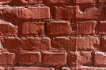 Red brick wall background. Close-up view of old painted red brick wall surface covered with cracks...