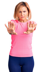 Fototapeta premium Young blonde woman wearing sportswear doing stop gesture with hands palms, angry and frustration expression