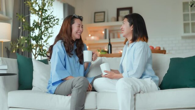 Asian woman friend group mature women meeting and sharing personal stories laughing at home while drinking coffee woman energetic women meeting and sharing personal stories in a living room warm house