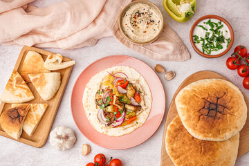 Tasty pita bread with grilled vegetables, hummus and sauce on white background