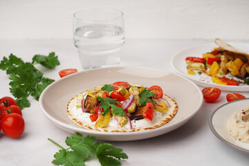Plate of tasty pita bread with grilled vegetables on white background