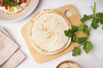 Wooden board of tasty pita bread on white background