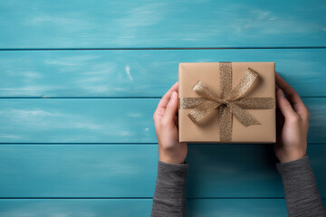  romantic blue background with male hands holding a wrapped gift box seen from above for a birthday 
