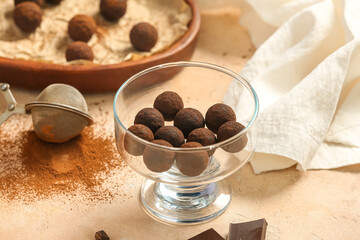 Bowl with tasty chocolate truffles on beige background