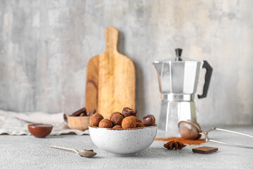 Bowl with tasty chocolate truffles on grey background