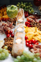 Gourmet Charcuterie Board with Bread, Grapes, Nuts, Chips, and Candlelight