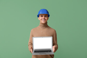 Young male engineer showing laptop with blank screen on green background