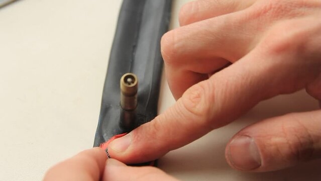 A man's hand seals a patch on a bicycle patch