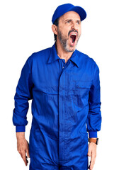 Middle age handsome man wearing mechanic uniform angry and mad screaming frustrated and furious,...