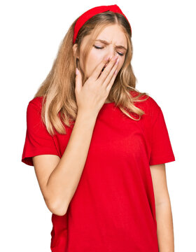 Beautiful young caucasian girl wearing casual red t shirt bored yawning tired covering mouth with hand. restless and sleepiness.