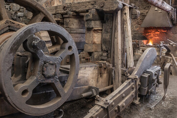 Historic machinery in a blacksmiths worksshop. - obrazy, fototapety, plakaty