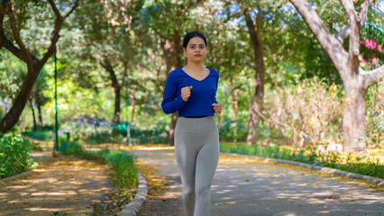Young woman running in the park at morning, also known as jogging or morning walk